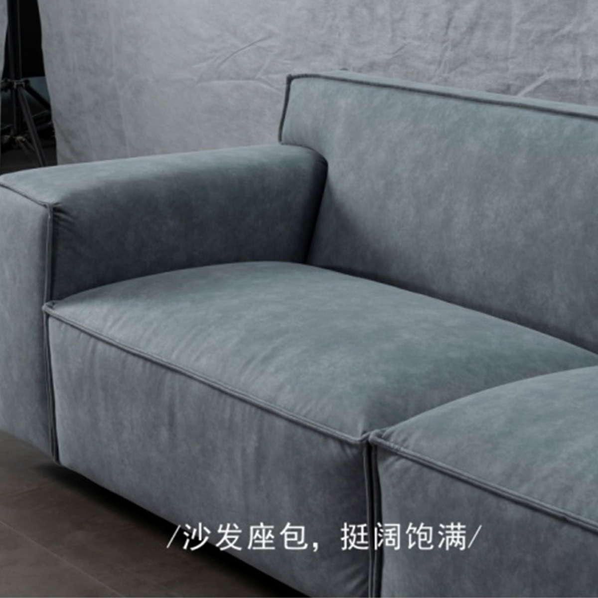 Close-up view of the grey sofa seat cushion and armrest showing fabric texture.