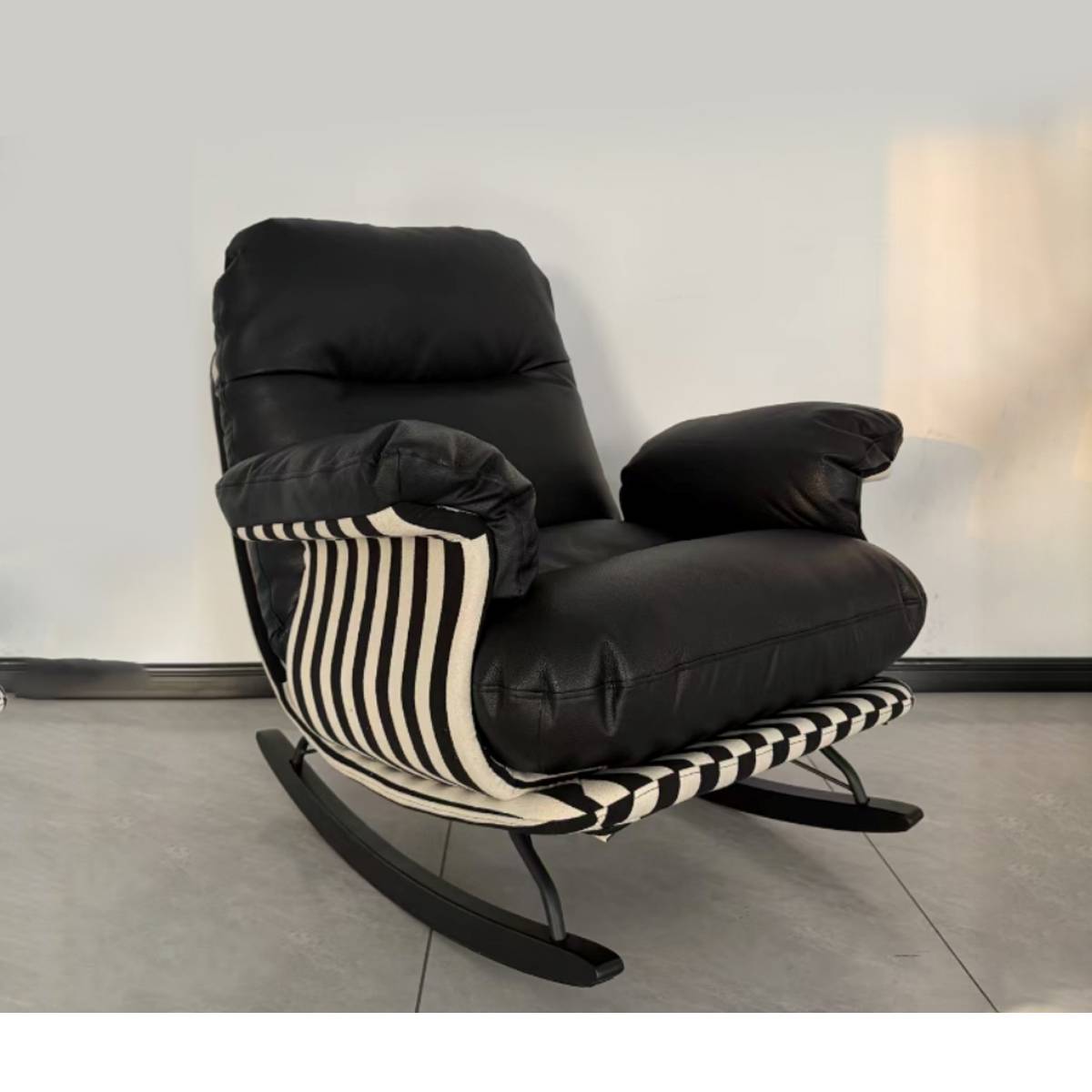 Side view of a black leather rocking chair with striped fabric armrests and base