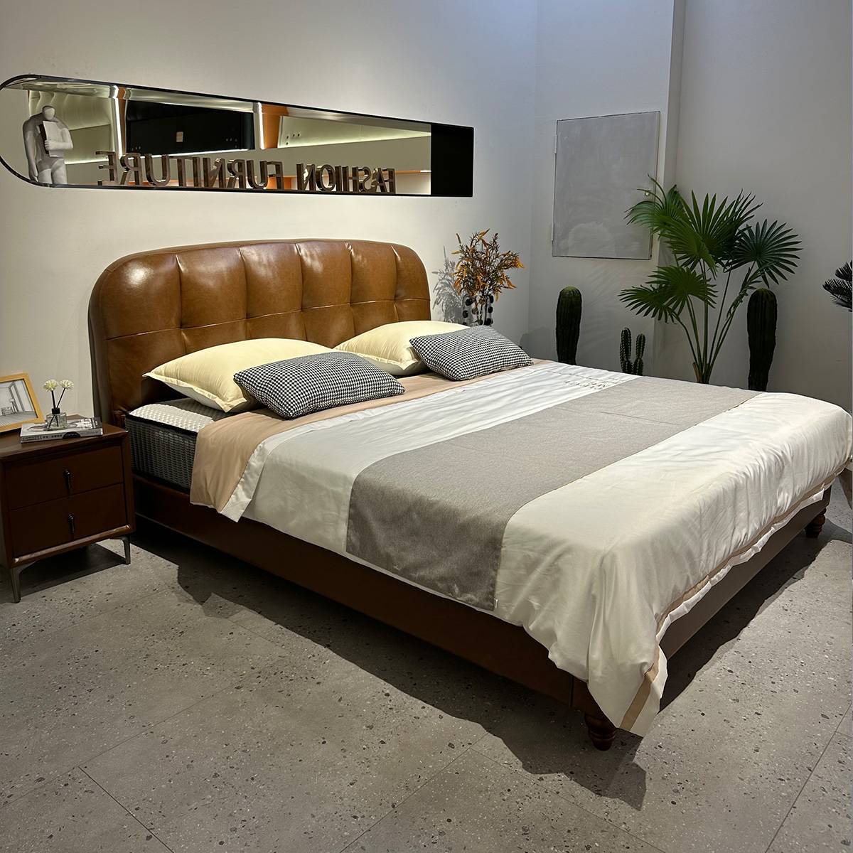 Full view of the brown leather bed with bedding and bedside table
