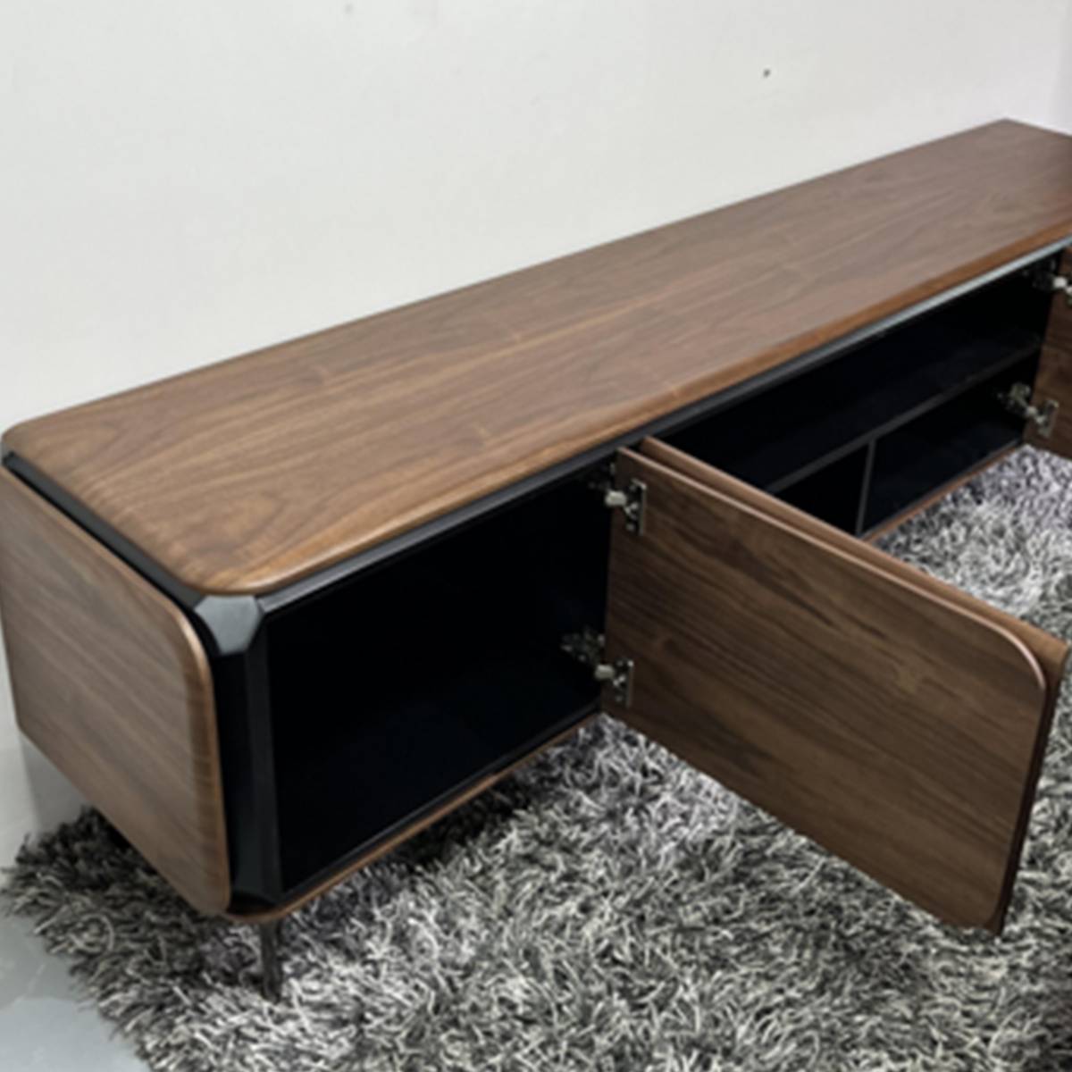 Side view of the TV console with cabinet doors open, revealing black interior storage compartments.