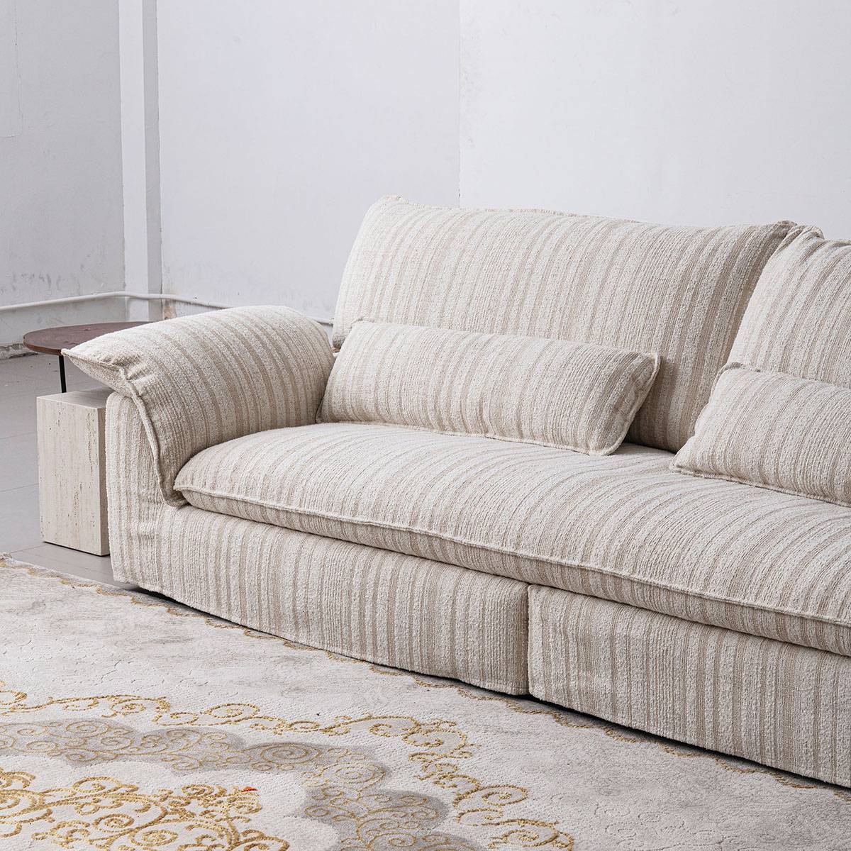 Full view of the beige striped fabric sofa in a bright living room setting with a wooden coffee table.