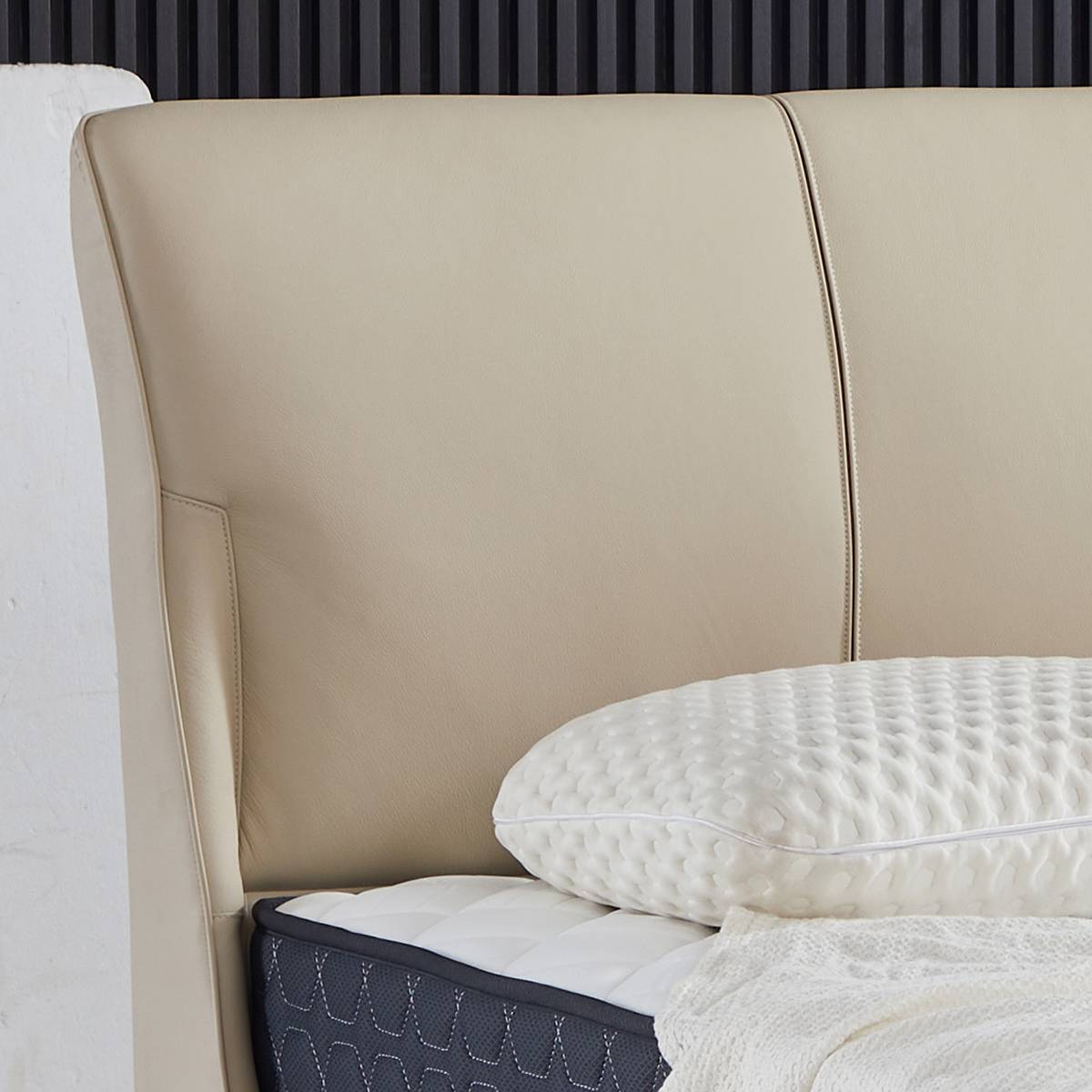Close-up of beige leather headboard with white textured pillow