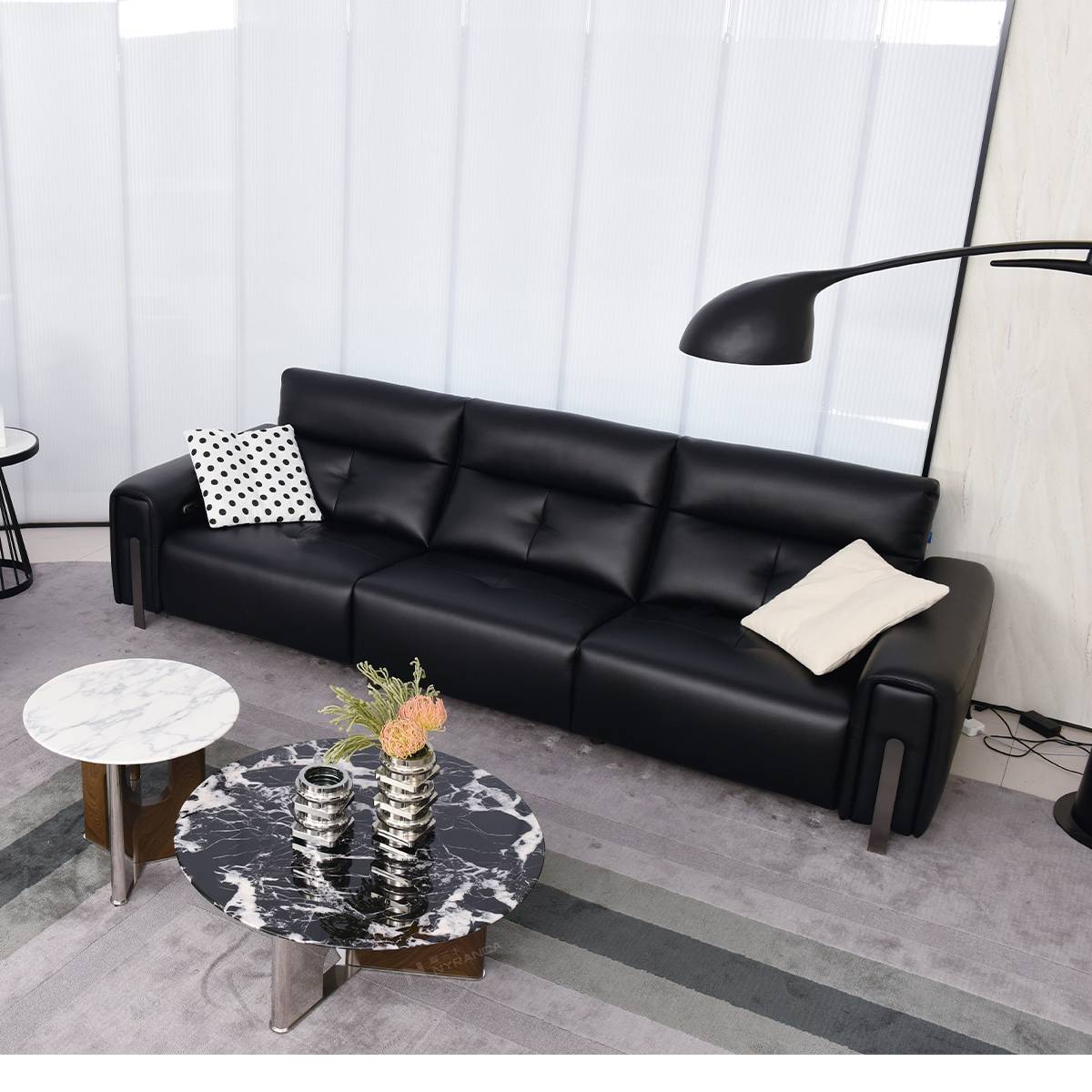 Wide angle view of the black sofa in a living room setting with two coffee tables