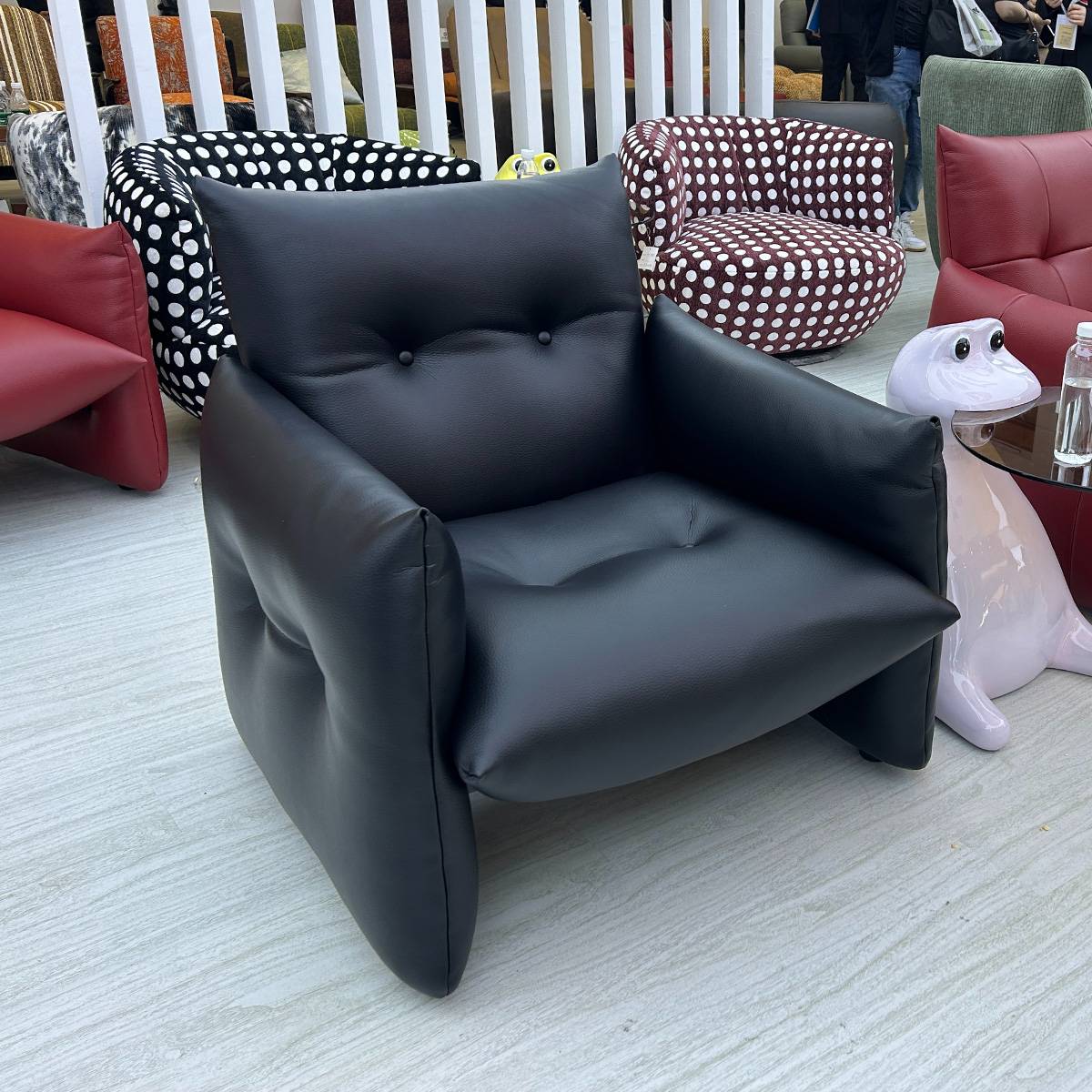 The black lounge chair displayed in a showroom setting with other furniture