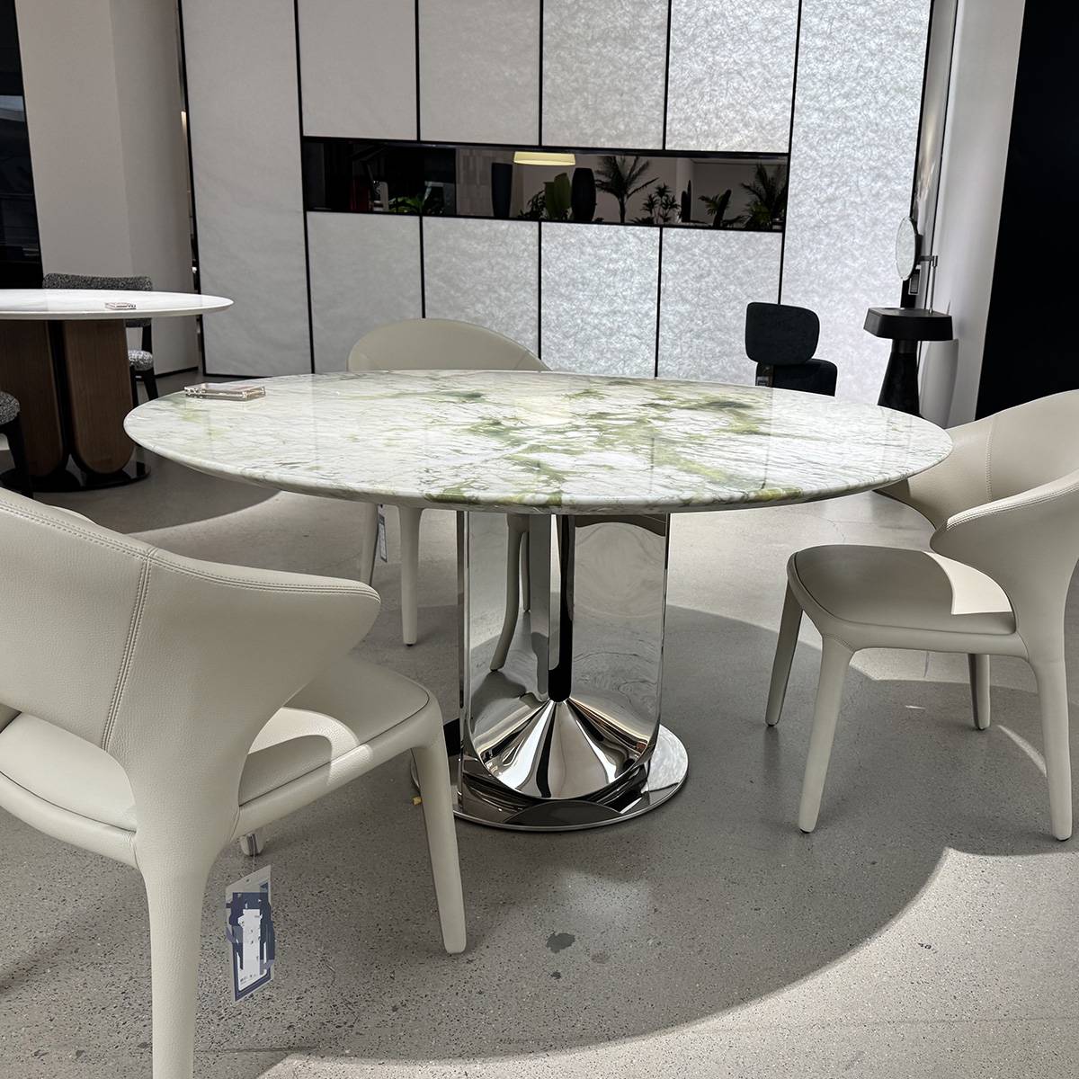 Lifestyle shot of the dining table in a showroom setting with white chairs