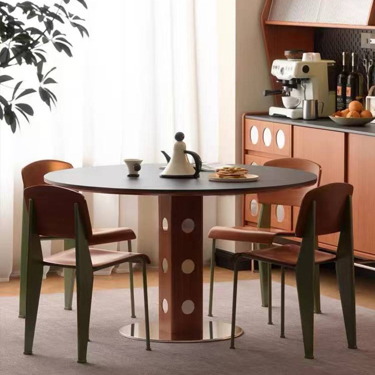 Black round dining table surrounded by four chairs with green legs