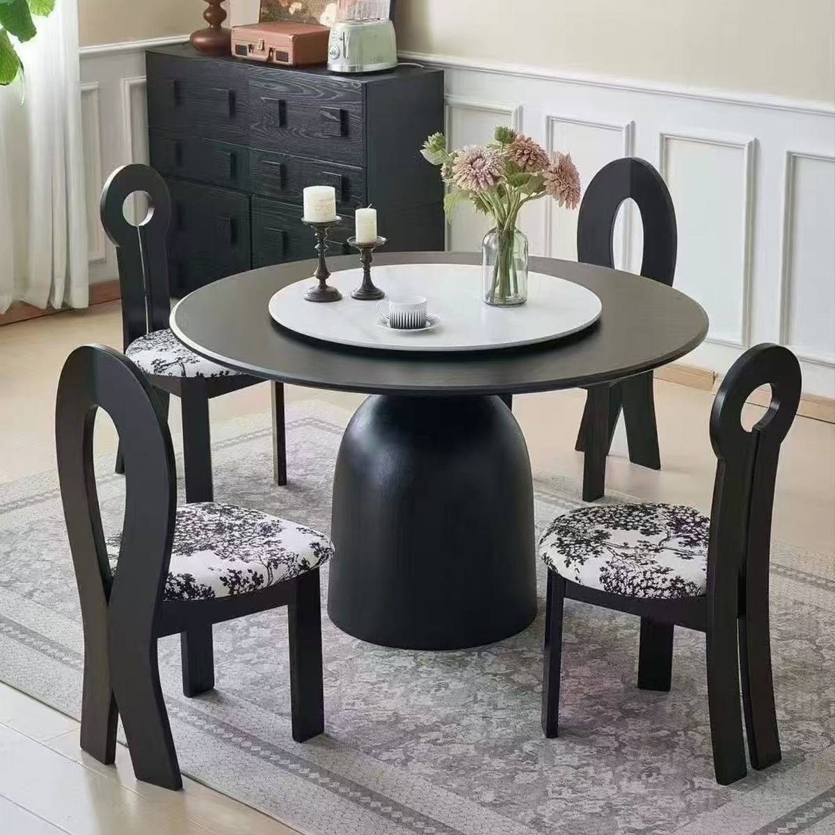 Dark grey round dining table with a white turntable and matching chairs with floral upholstery.