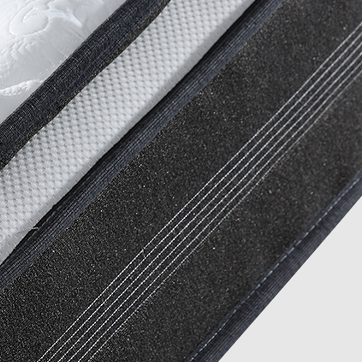 Close-up of the mattress corner showing the black reinforced edge and white textured surface
