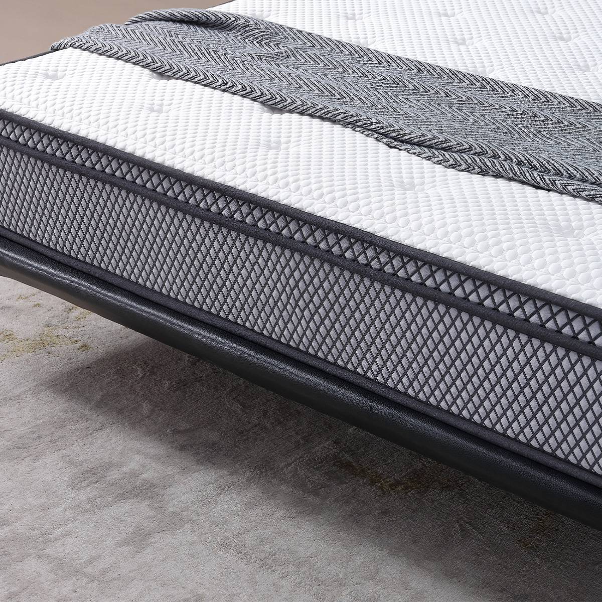 Close-up of the mattress surface showing white textured fabric and grey herringbone pattern