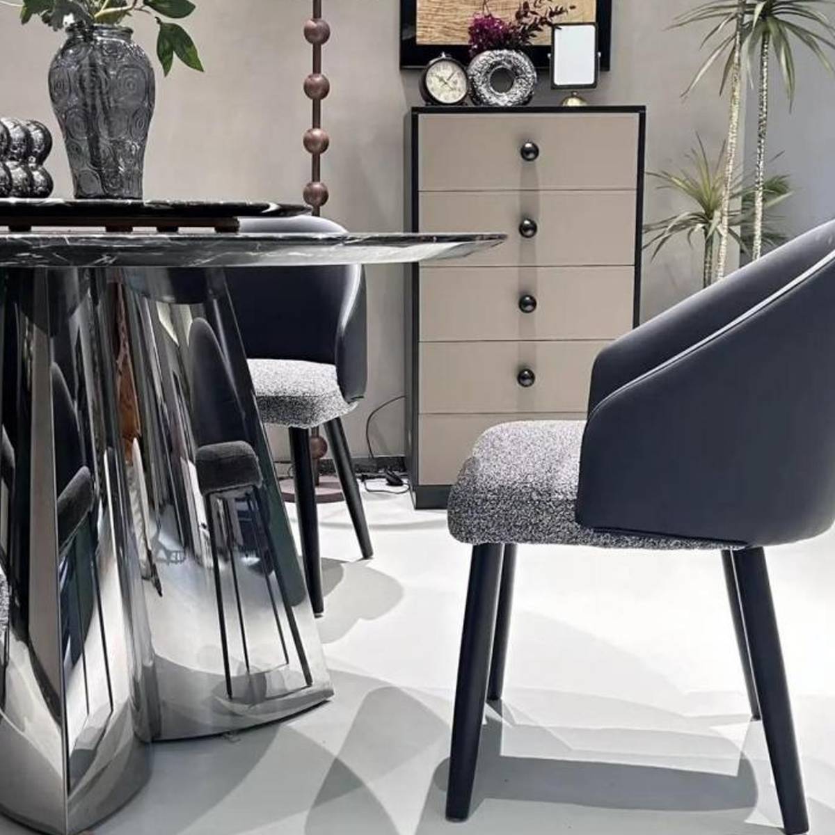 Close-up detail of the stainless steel mirror-finish clover base of the dining table.