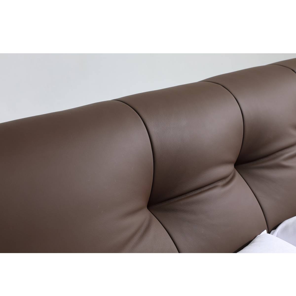 Close-up detail of the brown leather tufted headboard showing the stitching and texture.