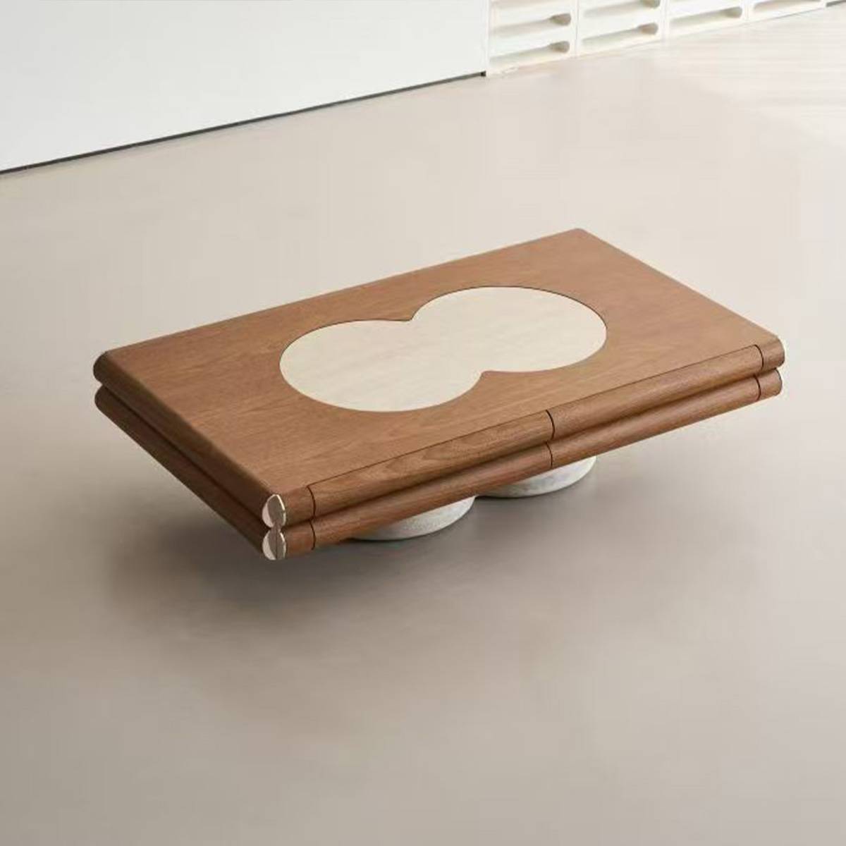 Angled view of the coffee table on a floor, highlighting the travertine base and stainless steel corner details.