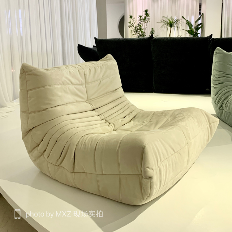 Cream colored quilted velvet lounge chair on a white display platform