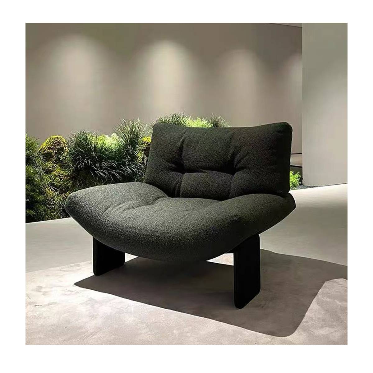 Dark green lounge chair displayed in a showroom with plants