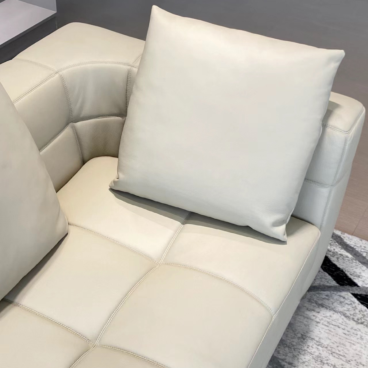 Close-up detail of the beige leather sofa cushion and armrest stitching