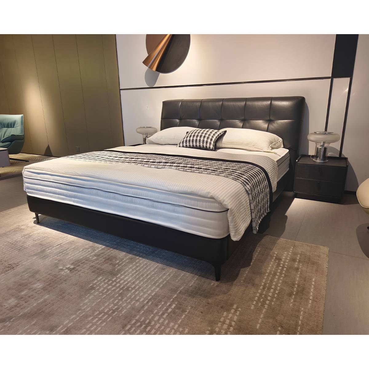 Close-up detail of the black leather tufted headboard and mattress.