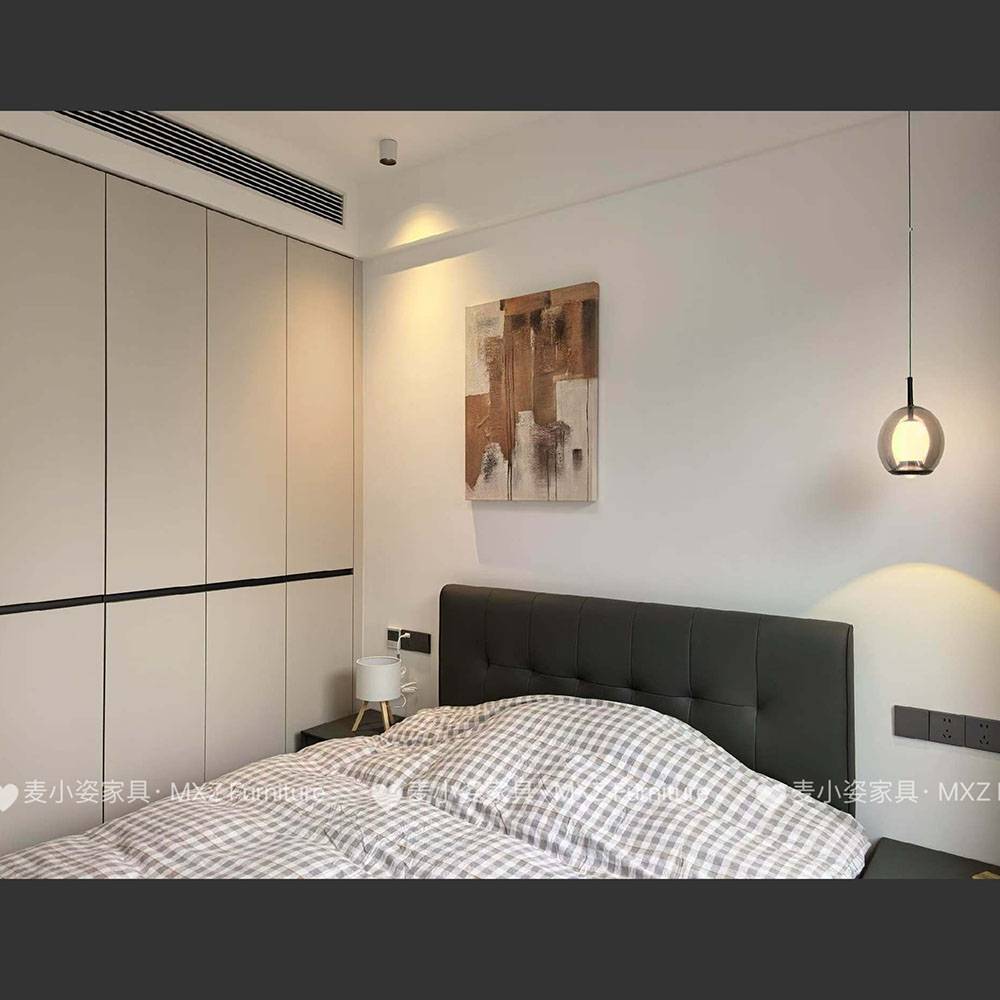 Bedroom with grey tufted bed, abstract wall art, and pendant light