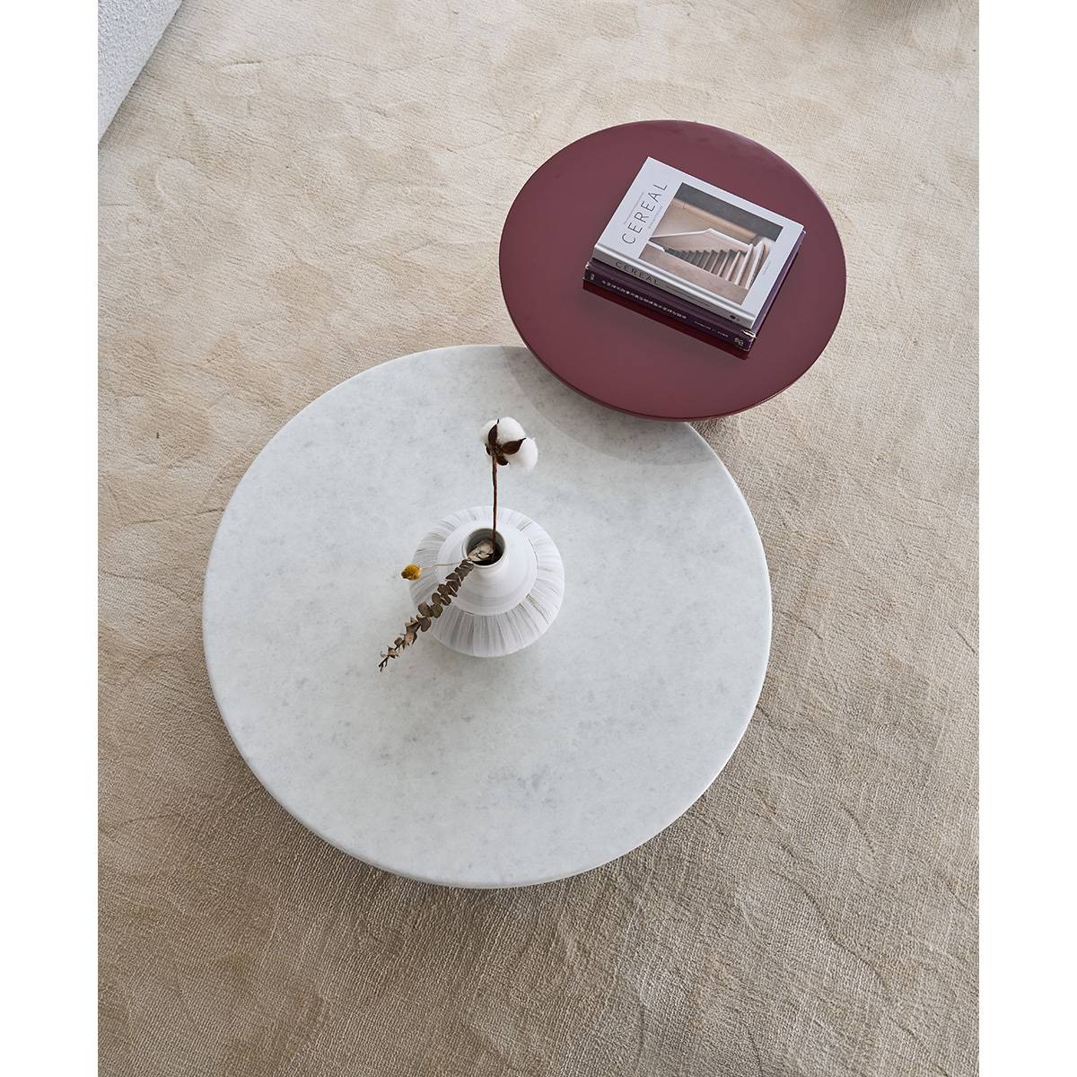 Top-down view of the coffee table set showing the white stone table and burgundy table on a beige rug.