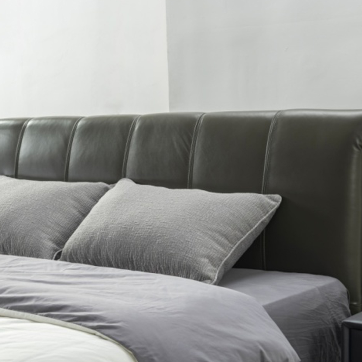 Close-up view of the grey leather bed headboard with pillows