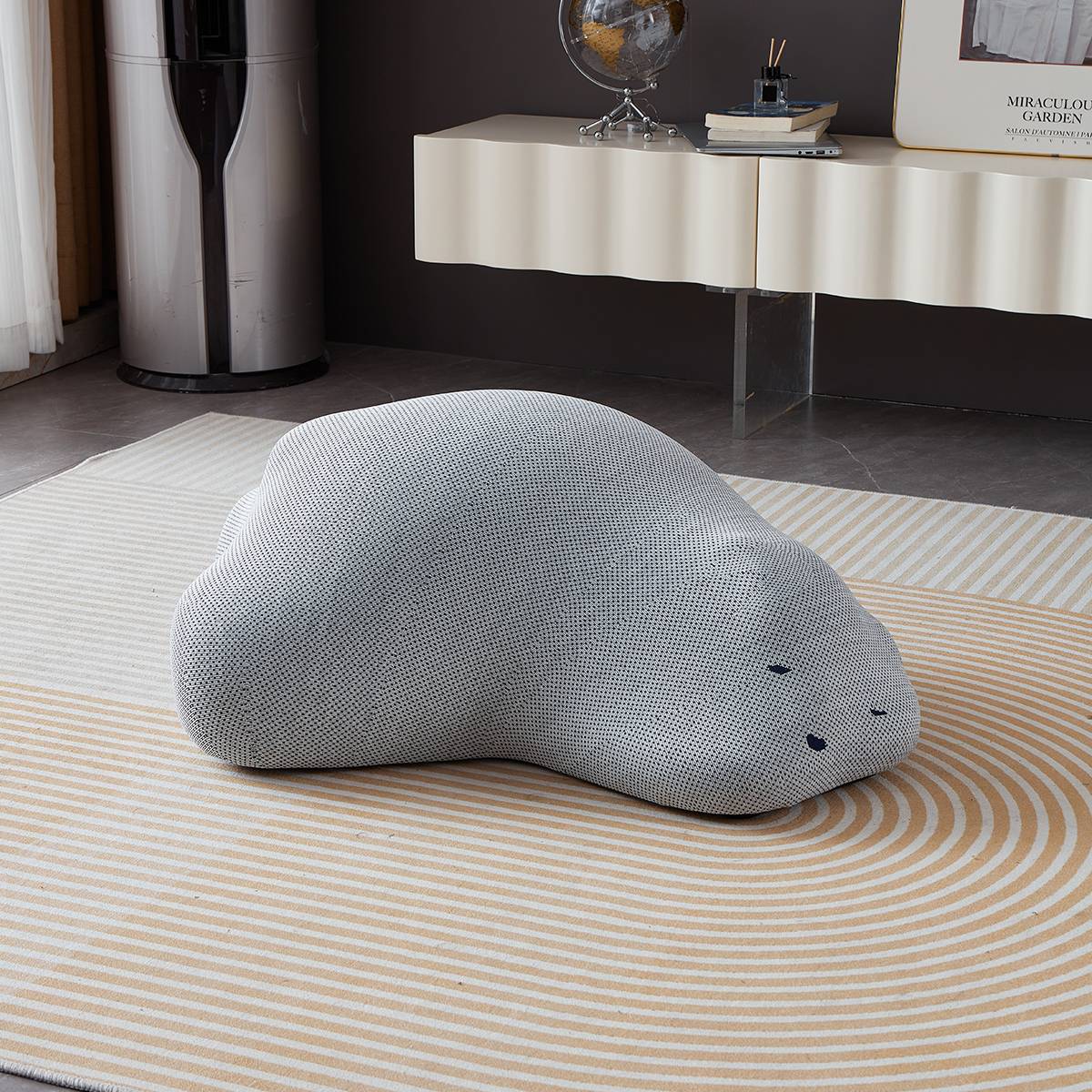 Grey textured bear-shaped stool on a striped rug