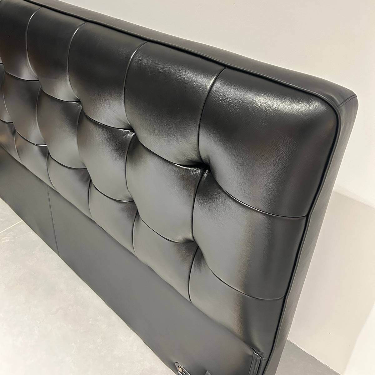 Close-up detail of the black tufted leather headboard